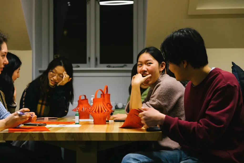 A group of students smils and laughs as they put together red lanterns for Lunar New Year.