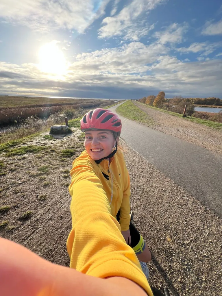 Caroline smiles mid-bike ride in the Danish countryside.